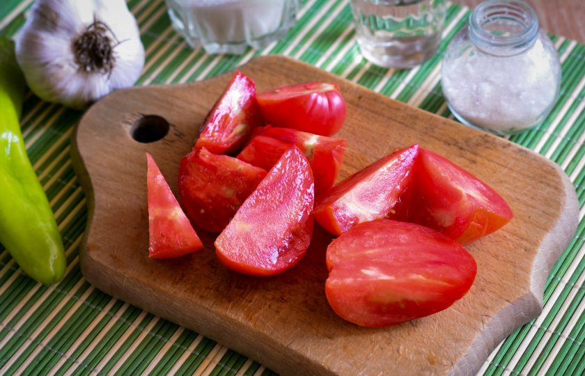 1. Этап. Острая приправа из помидоров и острого перца: Помидоры промойте и нарежьте дольками, срезая плодоножку.