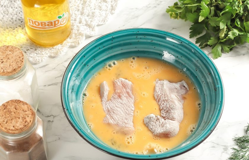 1. Этап. Наггетсы на сковороде: Взбейте куриное яйцо в глубокой емкости. В сковороде с высокими бортиками или в ковше с антипригарным дном разогрейте до кипения растительное масло. Обмакните филе во взбитое яйцо.