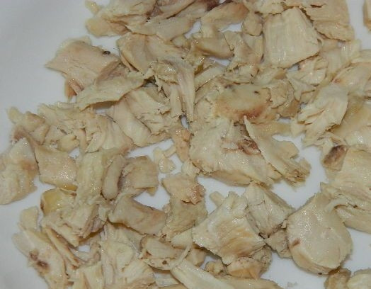 1. Этап. Салат с курицей и сыром: 3. С готовой холодной курицы снимите шкурку и нарежьте мясо на небольшие кусочки. Выложите курицу первым слоем в блюдо, в котором будете подавать салат. Слоеным он получается намного вкуснее.