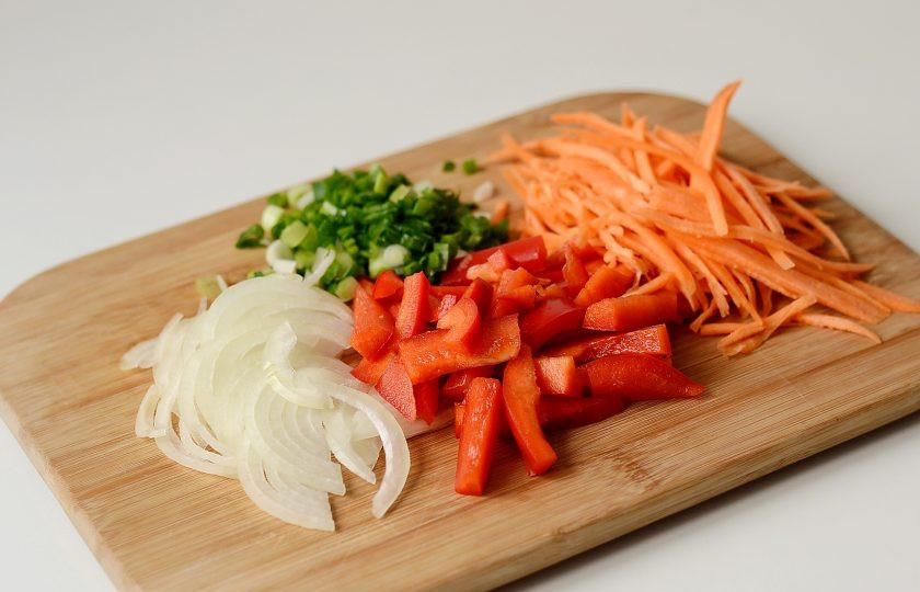 1. Этап. Вок рисом и овощами: В это время подготовьте овощи. Лук нарежьте полукольцами, болгарский перец соломкой, а морковь натрите на корейской терке. Зеленый лук крупно порубите.