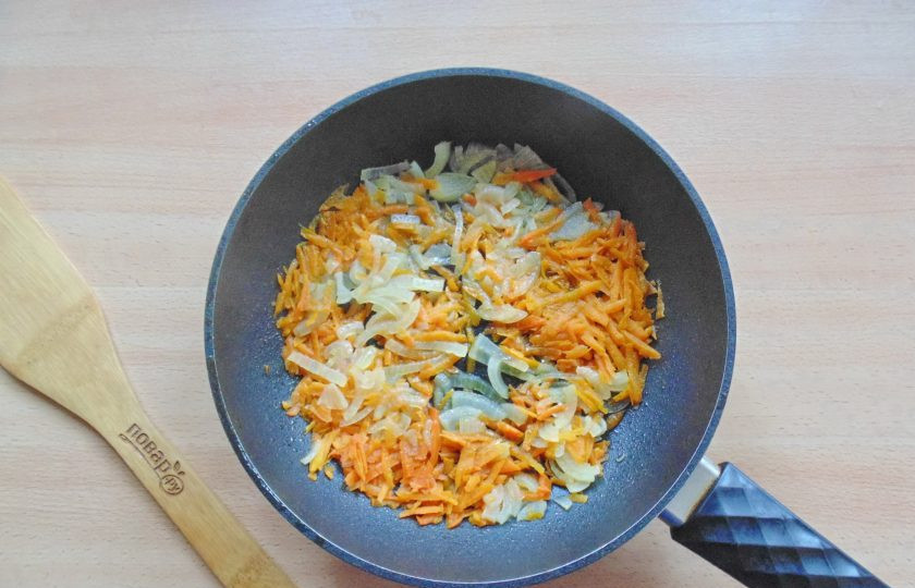 1. Этап. Хек с кабачками в духовке: Обжарьте лук и морковь на среднем огне до мягкости.