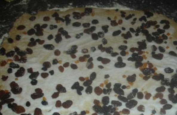 1. Этап. Гата с творогом: Разделите тесто на 2 равных части, каждую раскатайте в тонкий пласт. Присыпьте тесто сахаром и изюмом.