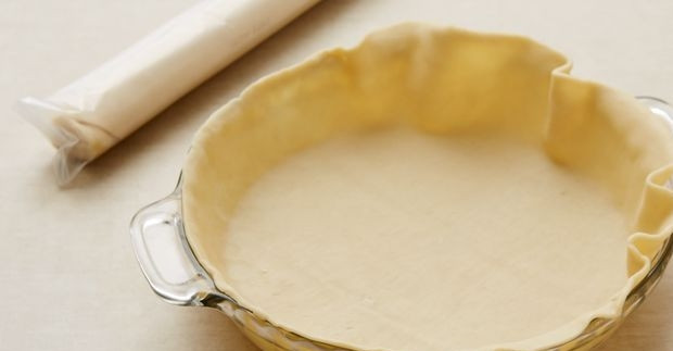 1. Этап. Пирог с лимоном и яблоками: 1. Разделите тесто на 2 части. Раскатайте обе части в пласт около 0,5-0,8 сантиметра в толщину. Выложите 1 часть в смазанную сливочным маслом форму, прижмите руками тесто к бокам и к низу формы.