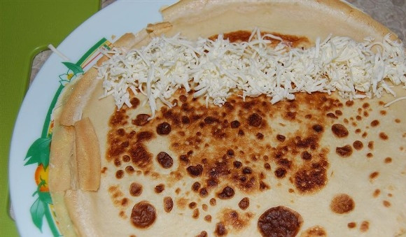 1. Этап. Блины с семгой и сыром: Переворачиваем блины более поджаренной стороной вверх, и на край блина выкладываем натертый сыр.