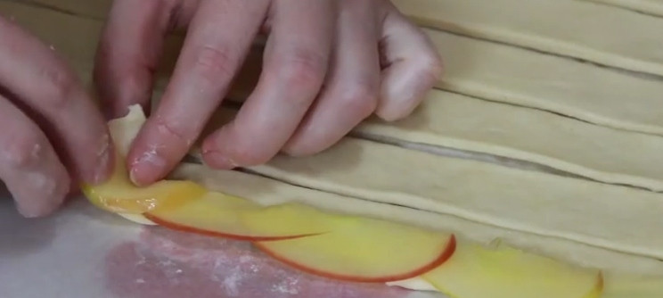 1. Этап. Легкий рецепт десерта: Тесто разморозьте и порежьте на небольшие полосочки, выкладывайте яблоки внахлест. Сворачивайте каждую полосочку, формируя розу.