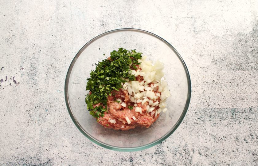 1. Этап. Пирожки с кабачком и фаршем: В миску выложите фарш, мелко нарезанные репчатый лук и укроп.