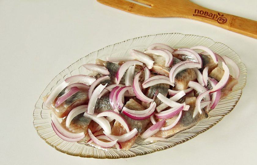 1. Этап. Сельдь в сырном соусе: Сверху выложите нарезанный полукольцами или перьями лук и полейте растительным маслом.