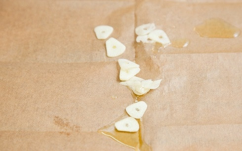 1. Этап. Запеченный палтус: 1. Духовку включите и разогрейте до 180 градусов. На лист пергамента вылейте ложку оливкового масла и выложите нарезанный чеснок.