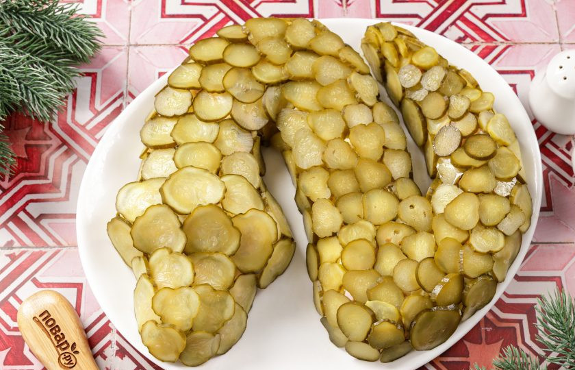 1. Этап. Салат Оливье на год Змеи: Маринованные огурцы нарежьте тонкими кружочками. Желательно взять небольшие сорта, без крупных семечек. Обкладываем всю змею нарезанными огурцами, имитируя кожу змеи.