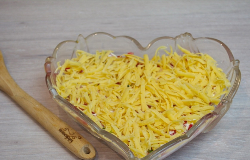 1. Этап. Салат Петушок с курицей и помидорами: Натрите на крупной терке твердый сыр. Сыр выложите на салат ровным слоем.