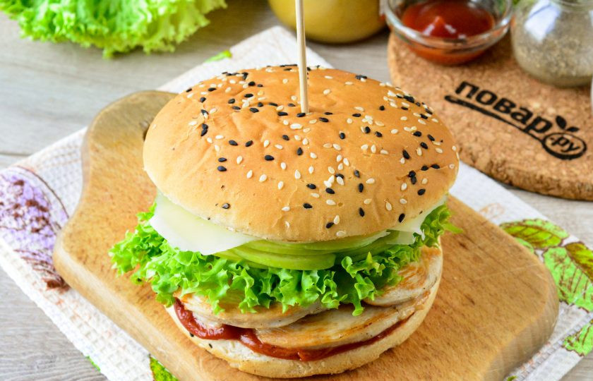 1. Этап. Бургер с курицей, яблоком и сыром: Прикройте бургер второй половинкой булки, ее также снизу смажьте соусом. Готовый бургер зафиксируйте шпажкой и готово.