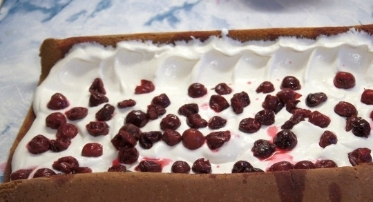 1. Этап. Бисквитный рулет с вишней: На бисквит выложите вишни. Перед этим их следует очистить от косточек и замочить в роме на полчаса, а затем слить лишнюю жидкость. Тесто с начинкой сверните в рулет и поставьте в холодильник на несколько часов.