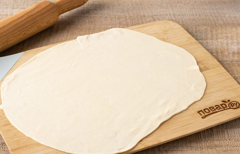 1. Этап. Слоёные лепёшки с луком Катлама: Разделите тесто на 4 части. Присыпьте мукой каждую часть и тонко раскатайте примерно в 2-3 мм.