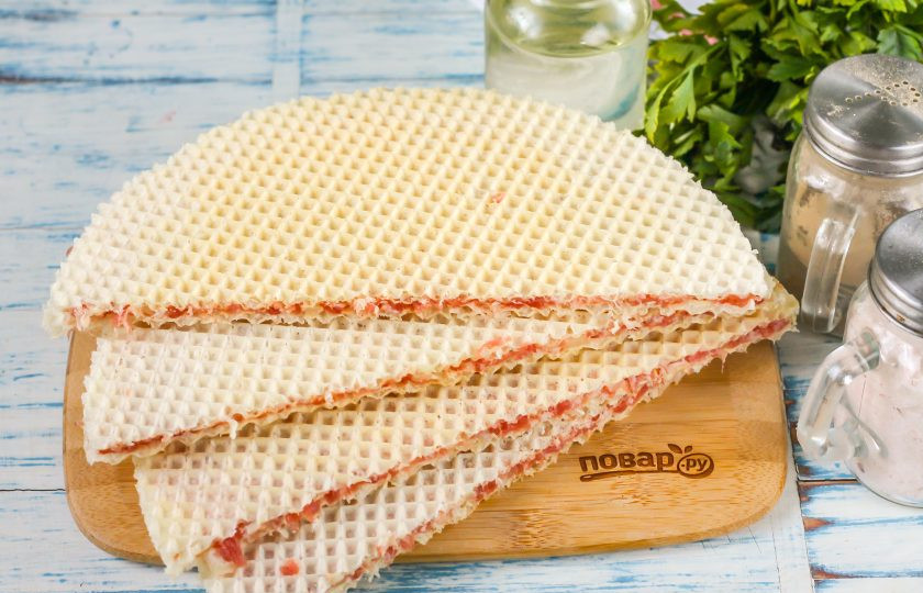 1. Этап. Чебуреки из вафельных коржей: Накройте вторым коржом и слегка прижмите. Отставьте в сторону. Обмажьте еще один корж оставшейся половиной фарша. Накройте четвертым коржом и прижмите. Оставьте на 5 минут. Затем поместите одну заготовку на другую и разрежьте обе их пополам, получая заготовки чебуреков. За 5 минут коржи пропитаются и легче разрежутся, а не поломаются на части.