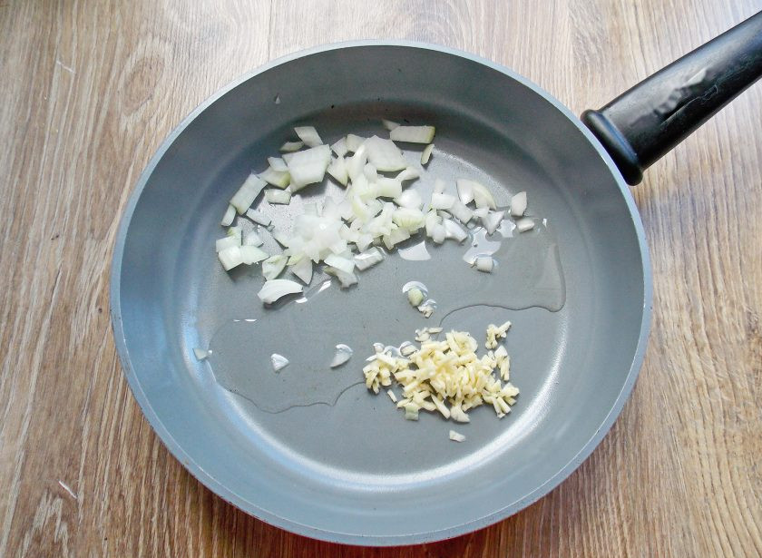 1. Этап. Кускус с баклажанами: Репчатый лук и чеснок почистите и мелко порежьте. В сковороду налейте растительное масло, разогрейте на среднем огне и выложите порезанные чеснок и лук.