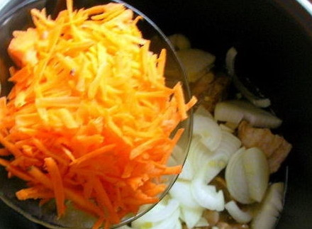 1. Этап. Свинина с рисом в мультиварке: В чашу мультиварки налить растительное масло, выложить мясо. Сверху слоями выложить лук с чесноком и морковь.