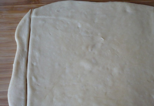 1. Этап. Булочки с плавленым сыром Ассорти: Теперь берем шарик теста и раскатываем его в форме прямоугольника. Края прямоугольника обрежьте с двух сторон как на фото. Остатки теста скатайте в шарик и на время отложите в сторону.