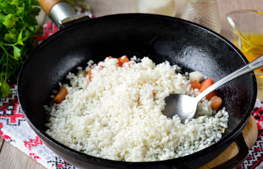1. Этап. Рассыпчатый рис в сковороде: Всыпьте в сковороду промытый рис и перемешайте. Добавьте по вкусу соль и перец.