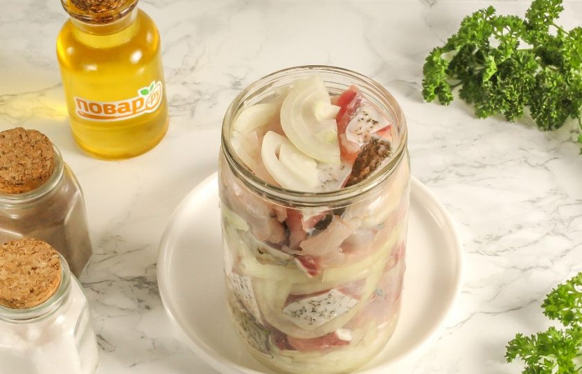 1. Этап. Селедка из толстолобика: Лук нарежьте полукольцами и поочередно выложите с нарезкой толстолоба в высокую банку или стеклянную емкость, которая закрывается. Оставьте сверху чуть пространства, чтобы можно было добавить специи и масло.