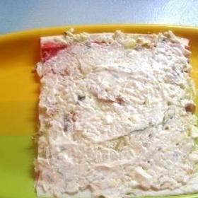 1. Этап. Крабовый торт: На развернутую крабовую палочку тонким слоем намазываем начинку нашего салата, которая состоит из смешанных майонезом отварного риса, натертых на среднюю терку яиц и соленых огурцов, и мелких кусочков семги.