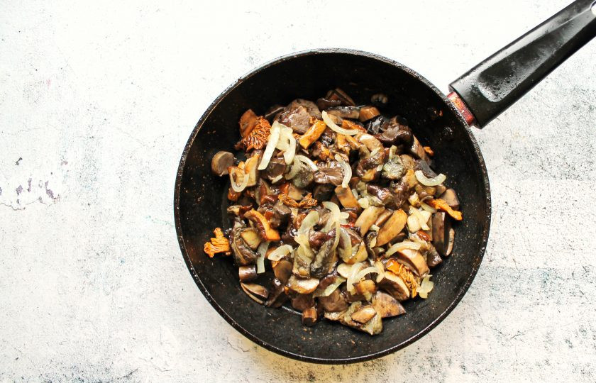 1. Этап. Грибы на сковороде со сметаной и сыром: Грибы переберите, очистите от мусора и грязи, промойте и дайте воде полностью стечь. Если грибы чистые, просто протрите их влажной салфеткой. Порежьте грибы на дольки и обжаривайте в течение 5 минут на среднем огне. Репчатый лук порежьте и добавьте к грибам. Обжаривайте все еще 7 минут, перемешивая.