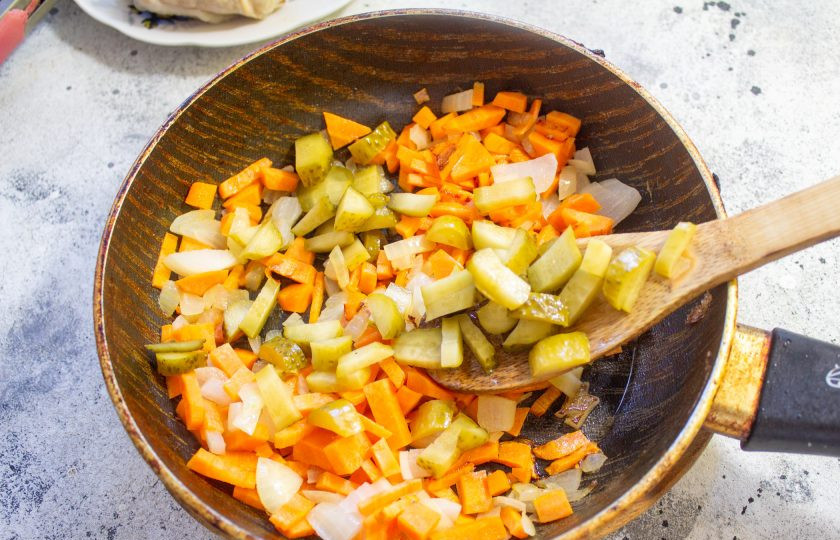 1. Этап. Куриный суп с солеными огурцами: Лук и морковь очистите и нарежьте мелким кубиком. Обжарьте до мягкости на растительном масле. Добавьте мелко нарезанные соленые огурцы и готовьте вместе еще пару минут.