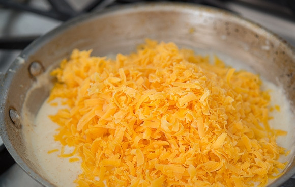 1. Этап. Сырный соус к начос: 4. За это время натрите на терке сыр. Кипящий соус снимите с огня, выложите на сковороду сыр.