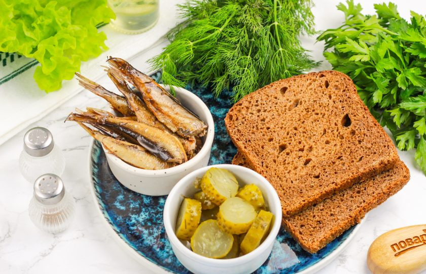 1. Этап. Канапе со шпротой: Подготовьте указанные продукты. Вскройте консервы, соленые огурцы промойте от рассола и нарежьте ломтиками. Оставьте нарезку на 5 минут, чтобы из нее выделился рассол. Если этого не сделать, то он пропитает ломтики хлеба и канапе будут влажные.