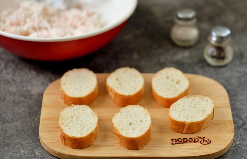 1. Этап. Бутерброды со сливочным сыром, киви и крабовыми палочками: Багет нарежьте порционными ломтиками толщиной 0,5-1 сантиметр.