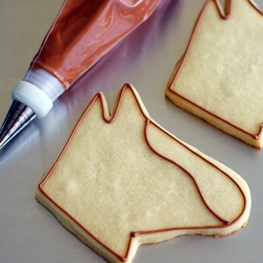 1. Этап. Печенье Лошадь: 1. Сначала приготовим печенье. Для это в миске разотрите сахар с маслом. Добавьте яичные желтки и просеянную муку. Замесите тесто и на полчаса отправьте в холодильник. Раскатайте до 0,5 см толщины, выдавите формочками лошадок, намажьте их взбитым яйцом и выпекайте в разогретой до 190 градусов духовке до ярко-желтого цвета. Пусть печенье слегка остынет. Затем возьмемся за декорирование. Сначала - контуры