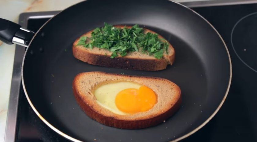 1. Этап. Суперсытный сэндвич на завтрак: 3. Затем переверните и в тот ломтик, где вырезан круг, добавьте яйцо и посолите. На другой ломтик положите мелко нарезанную зелень и тертый сыр. Накройте сковороду крышкой и оставьте на несколько минут.