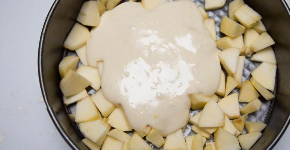 1. Этап. Быстрая яблочная шарлотка: Разъёмную форму смажьте маслом, и выложите половину яблок. Сверху залейте половину теста.