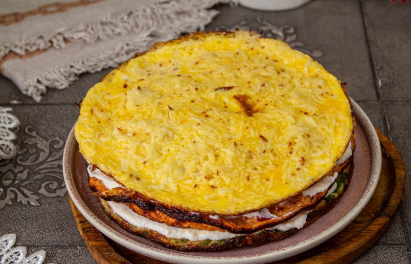 1. Этап. Трёхслойный торт-омлет: Соберите торт: выложите на блюдо омлет со шпинатом, смажьте половиной творожного крема. Затем омлет со шпинатом и снова сыр. Выложите третий омлет с сыром.