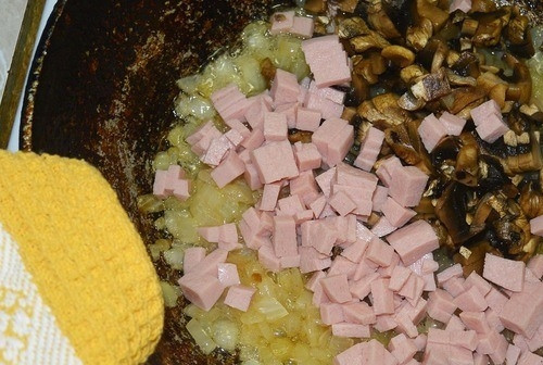 1. Этап. Французские макароны: Ветчину порежьте кубиками. Шампиньоны или же любые другие свежие грибы тщательно промойте и нарежьте кусочками, чтобы они были такого же размера, как и ветчина. Выложите оба ингредиента на сковородку, обжаривайте вместе с луком.