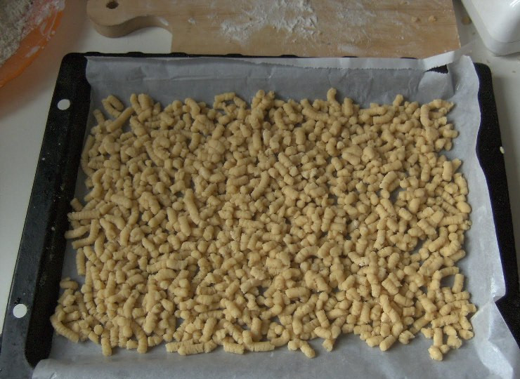 1. Этап. Печенье на майонезе через мясорубку: Застилаем противень пергаментной бумагой и смазываем ее маслом. Теперь немного обваливаем наших червячков в муке и выкладываем равномерно на противень.