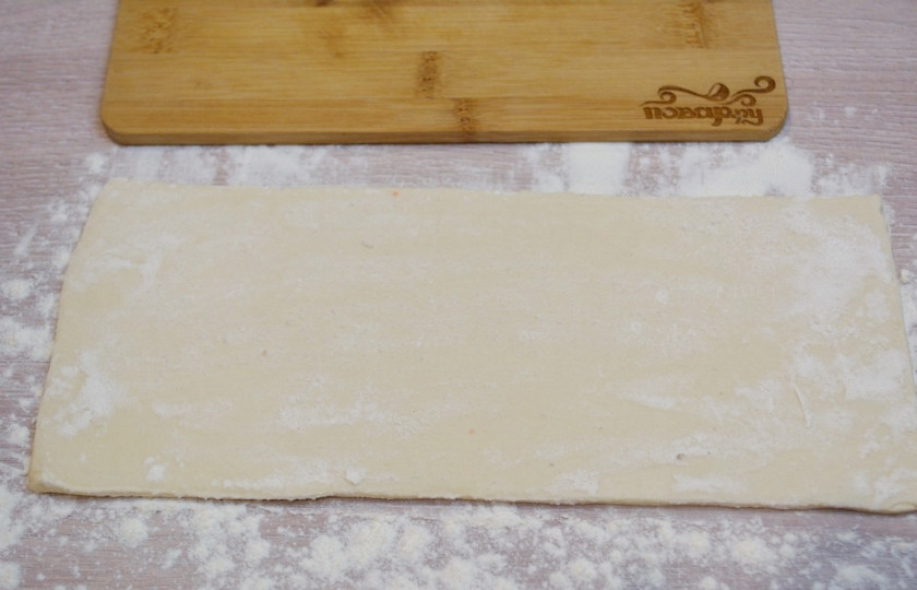 1. Этап. Хачапури из бездрожжевого слоеного теста: Для приготовления хачапури из бездрожжевого слоеного теста нужно взять листик слоеного теста. Дайте ему разморозиться при комнатной температуре. Присыпьте стол мукой, раскатайте лист в пласт. Используйте муку, чтобы скалка не 
