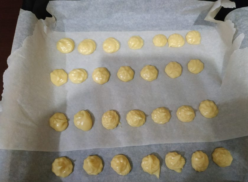 1. Этап. Торт Золотые купола: Выложите тесто в кондитерский мешок, сформируйте профитроли и отправьте в разогретую до 220 градусов духовку. Выпекайте 5 минут, затем убавьте температуру до 190 и оставьте профитроли еще на 20-25 минут. Основу торта выпекаем так же, разложив тесто на пергамент кругом, примерно 20-24 см в диаметре.