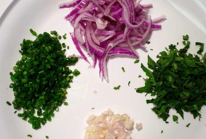 1. Этап. Салат с кальмарами и огурцами: Красный лук и лук-шалот очистите от шелухи, нарубите первый полукольцами, а второй — мелкими кубиками. Вымойте зелень, обсушите и также нарубите ее.