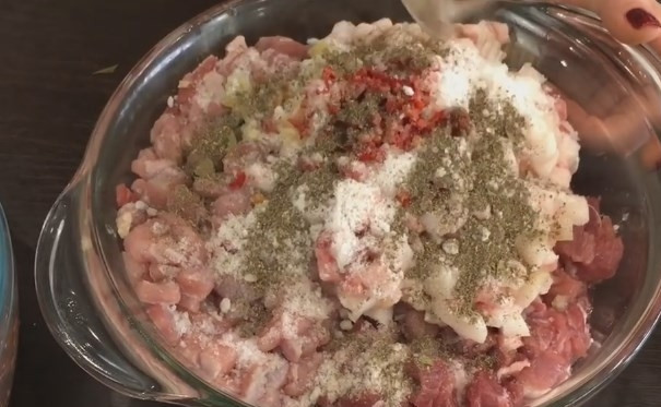 1. Этап. Вкусные и сочные домашние колбаски: 4. На одну половину мяса добавьте 1 чайную ложку перца, 1 лавровый лист и 0,5 чайной ложки кориандра. Хорошо вымешайте руками.