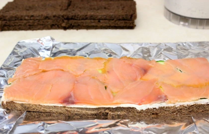 1. Этап. Торт с копченым лососем: Если вы купили ненарезанный лосось, нарежьте его на тонкие пластины. Рыбу нарезают с хвоста, держа нож под углом 30 градусов. Затем выложите поверх слоя огурцов.