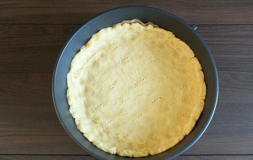 1. Этап. Киш с малиной: Возьмите форму для выпечки диаметром 26 см. Застелите ее пекарской бумагой. Выложите в форму тесто. Распределите его по дну, формуя высокие бортики. Основание пирога проткните вилкой. Поставьте в разогретую до 180 градусов духовку на 10 минут.