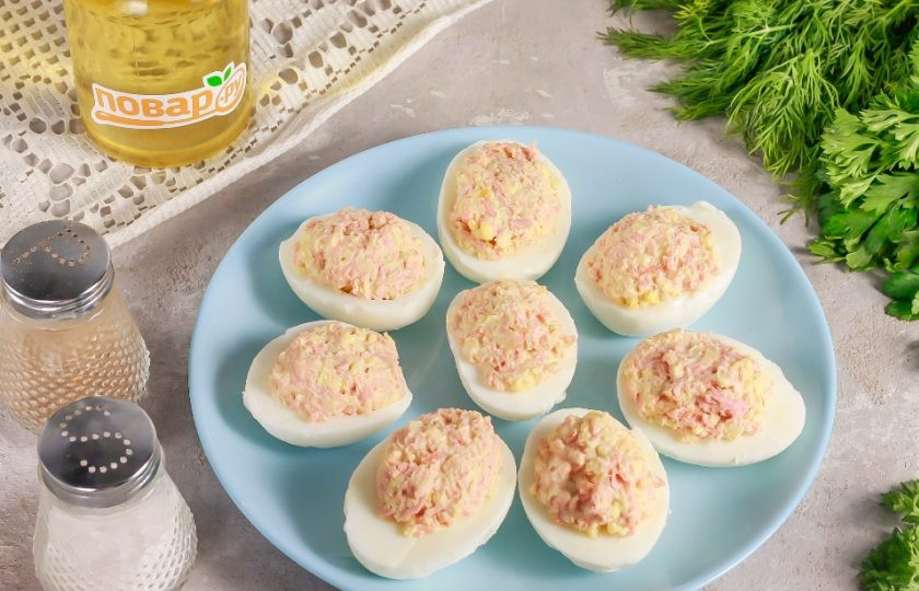 1. Этап. Яйца фаршированные вареной колбасой: С помощью чайной ложки начините оставшиеся белковые лодочки, выкладывая начинки чуть больше. Выложите все фаршированные яйца на тарелку или доску.