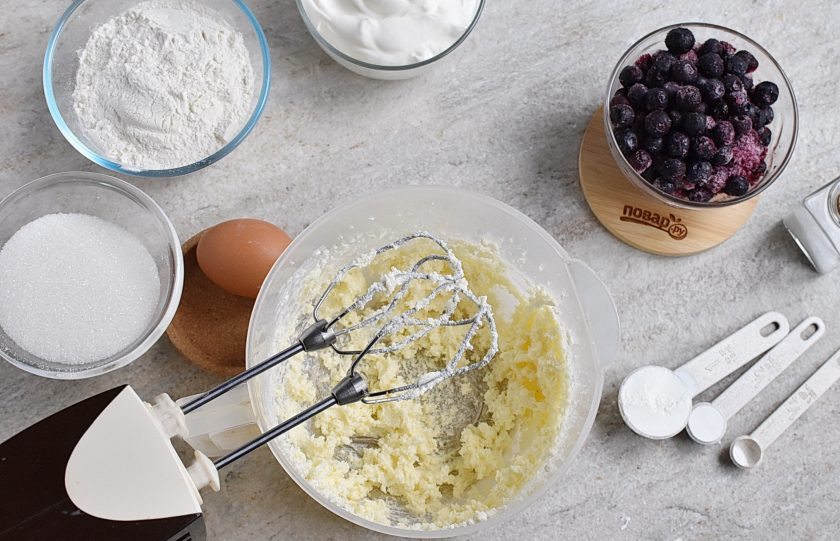 1. Этап. Черничный пирог со сметанной заливкой: Взбейте размягченное сливочное масло с 4 столовыми ложками сахара в пышную массу.