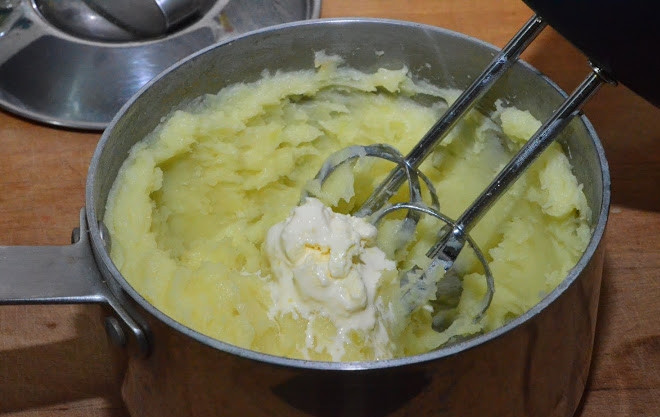 1. Этап. Картофельные котлеты в панировочных сухарях: Теперь нобходимо слить воду и превратить картофель в пюре. Для этого добавьте в кастрюлю сливочное масло и начинайте разминать картофель толкушкой или измельчать блендером. Когда пюре будет готово, добавьте к нему куриное яйцо и натёртый на крупную тёрку сыр.