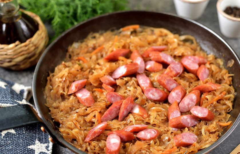 1. Этап. Бюргерская тушеная капуста: Колбаски нарежьте небольшими ломтиками, всыпьте в сковороду, перемешайте.