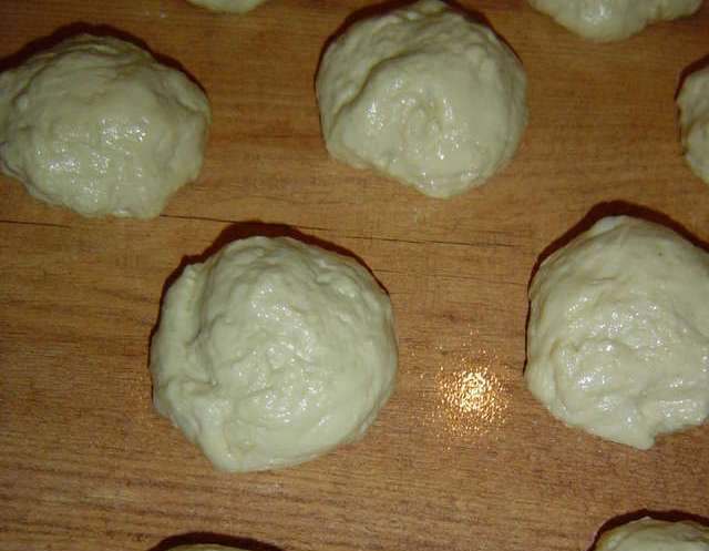 1. Этап. Пирожки с яблоками на сковороде: Когда тесто будет готово, мы смазываем стол и руки растительным маслом и выкладываем тесто на смазанную поверхность. Отделяем от него небольшие кусочки и формируем из них шарики. Выкладываем их все на стол и оставляем на 15 минут полежать.