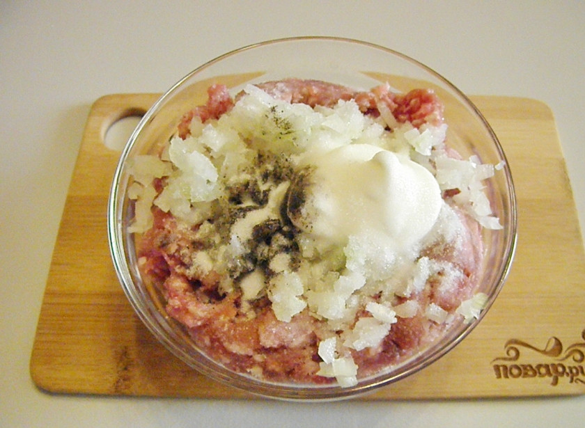 1. Этап. Бублики с фаршем в духовке: В готовый фарш (у меня вино-говяжий) добавьте половинку мелко порезанной луковицы, можно зубчик чеснока для аромата, соль, перец черный молотый и сметану. Перемешайте хорошо фарш.