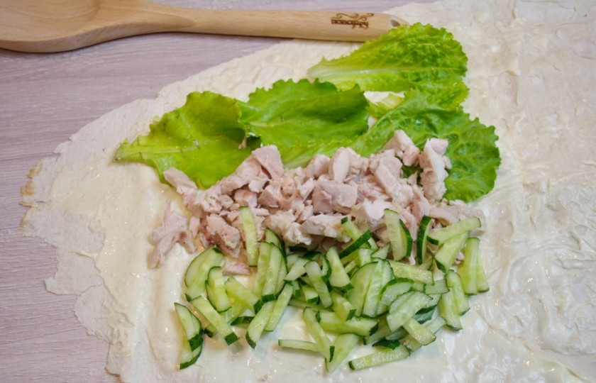 1. Этап. Рулетики из лаваша с курицей: Свежий огурец нарежьте соломкой или натрите на крупной терке. Свежие листья салата следует сначала вымыть, а затем уже нарвать руками. Отварное куриное мясо нарезаем мелко. На смазанную часть лаваша выложите подготовленные продукты линиями.