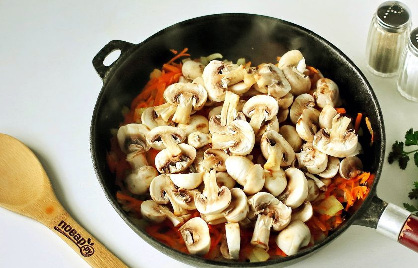 1. Этап. Грибной суп с галушками: Параллельно этому процессу, налейте в кастрюлю воду и доведите до кипения. Отдельно на сковороде обжарьте нарезанный кубиками лук и тертую морковь. В конце добавьте нарезанные шампиньоны и жарьте все вместе до испарения жидкости.