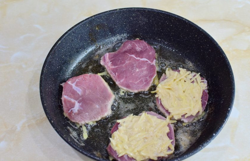 1. Этап. Свиные отбивные в картофельном кляре на сковороде: В горячую сковороду налейте растительное масло и выложите мясо кляром вниз. Сверху на мясо выложите еще кляр.